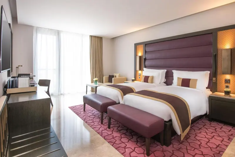 Chambre moderne avec deux lits simples et un espace détente.