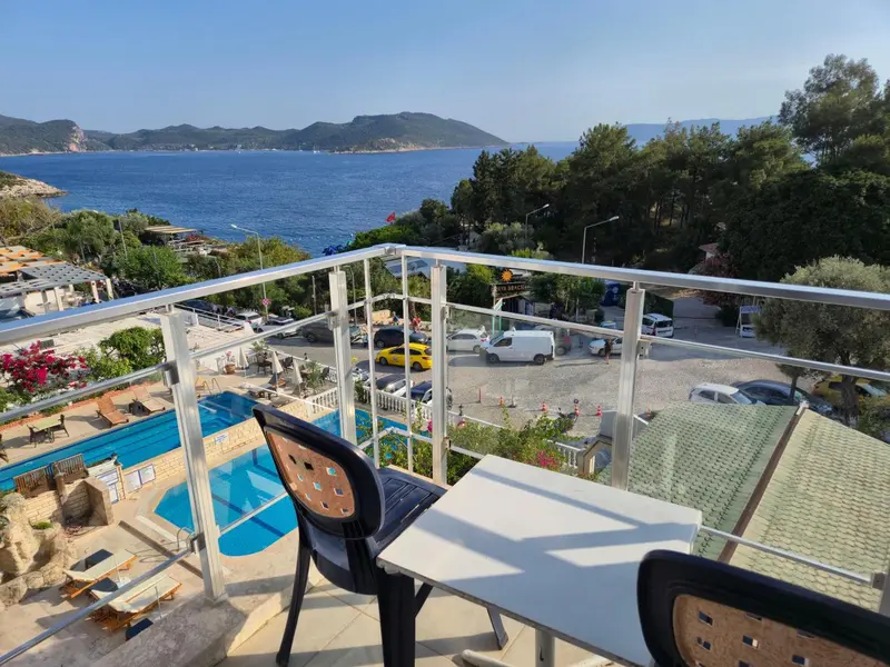 Vue d'une terrasse avec table et chaises donnant sur une piscine et la mer.