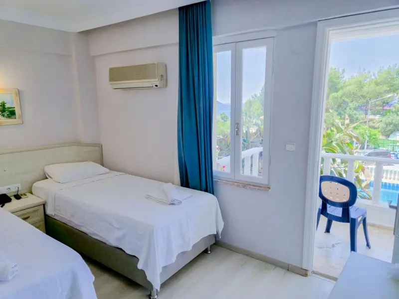 Une chambre lumineuse avec deux lits simples et une vue sur la mer.