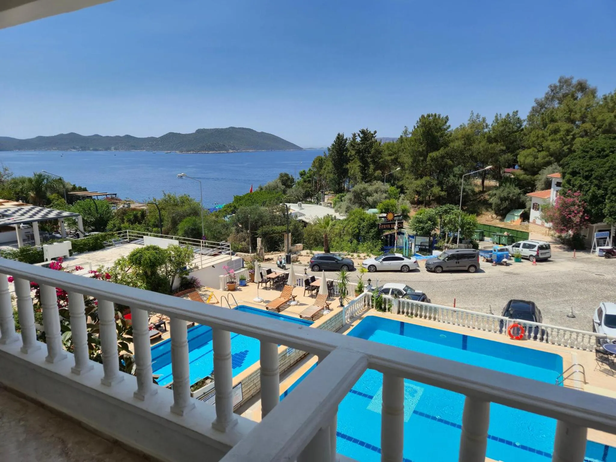 Vue d'une piscine et d'une terrasse surplombant la mer et la vegetation.