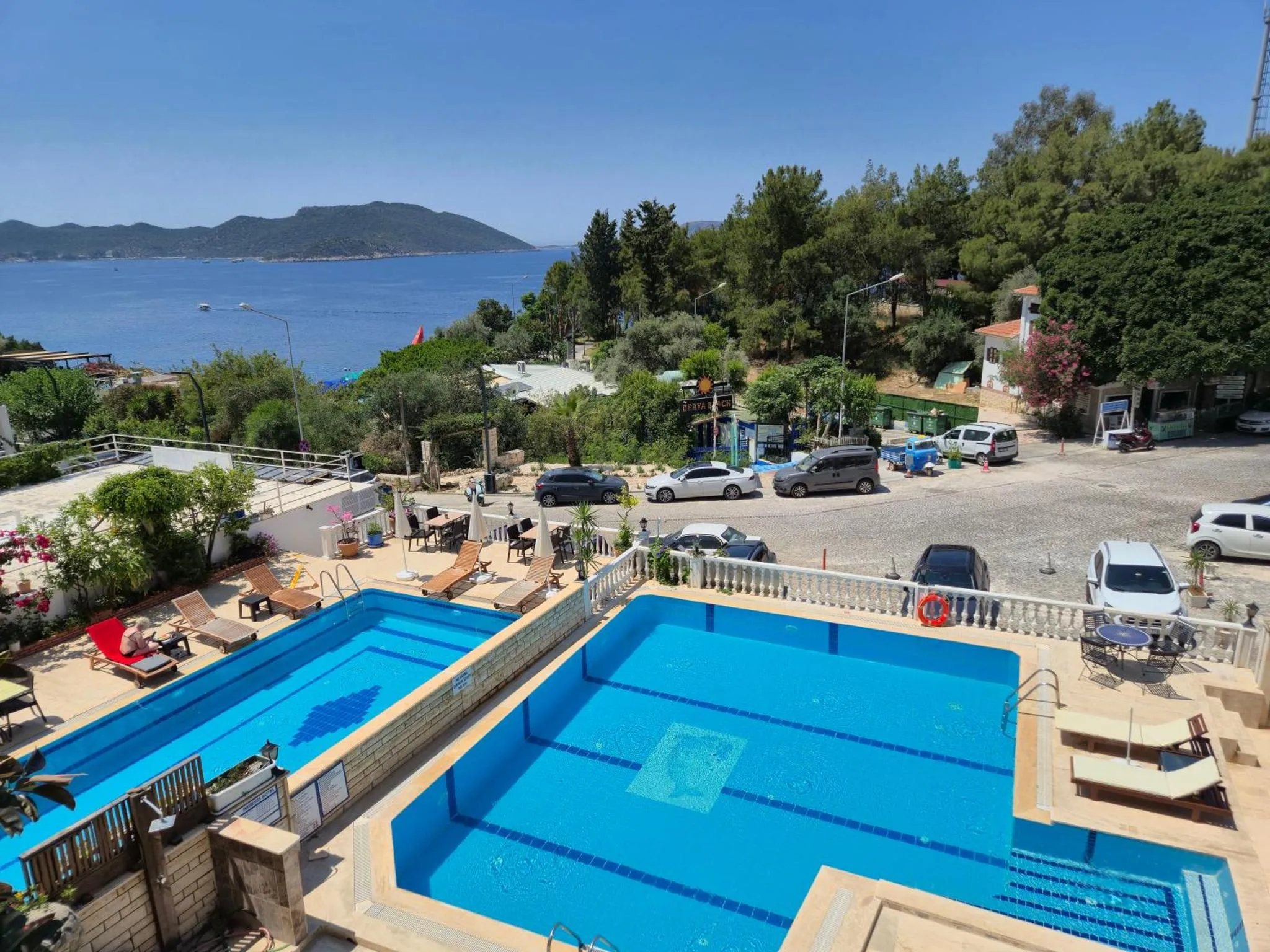 Deux piscines rectangulaires avec des transats et une vue sur la mer.