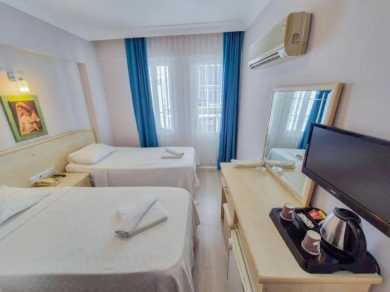 Une chambre lumineuse avec deux lits simples et un meuble téléviseur.