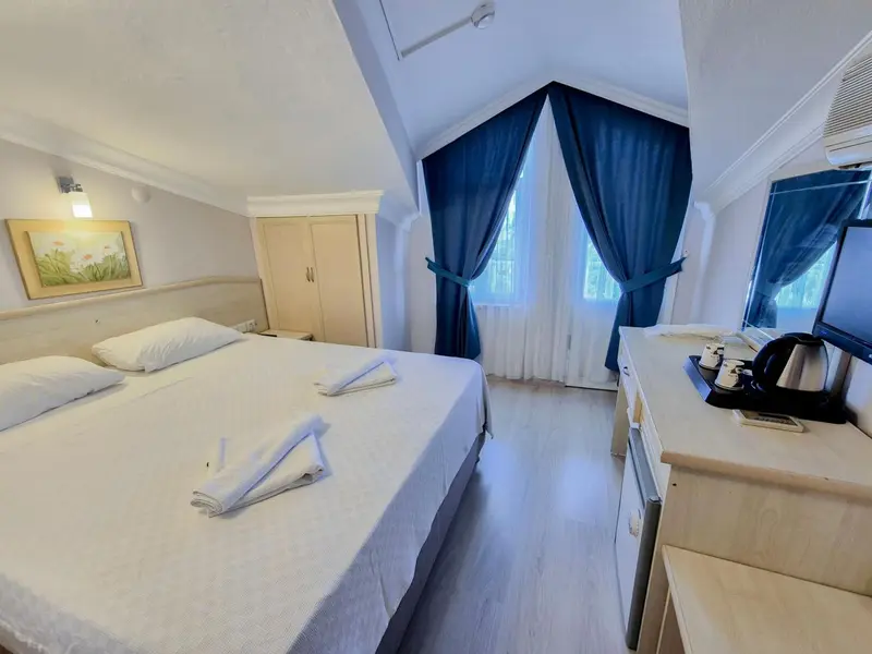 Une chambre lumineuse avec un lit double et un coin repos.