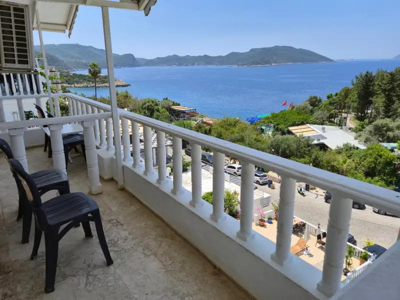 Vue d'une terrasse avec des chaises donnant sur la mer et les collines.