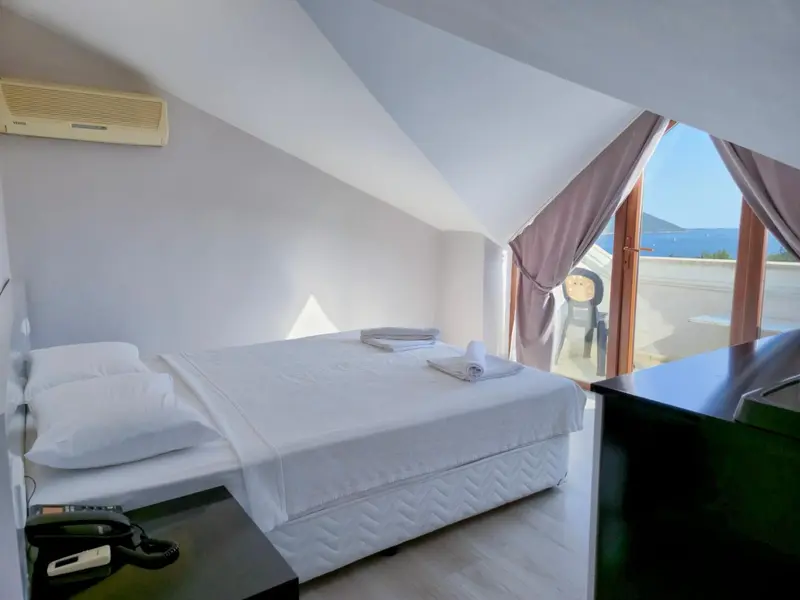 Une chambre lumineuse avec un lit blanc et une vue sur la mer.