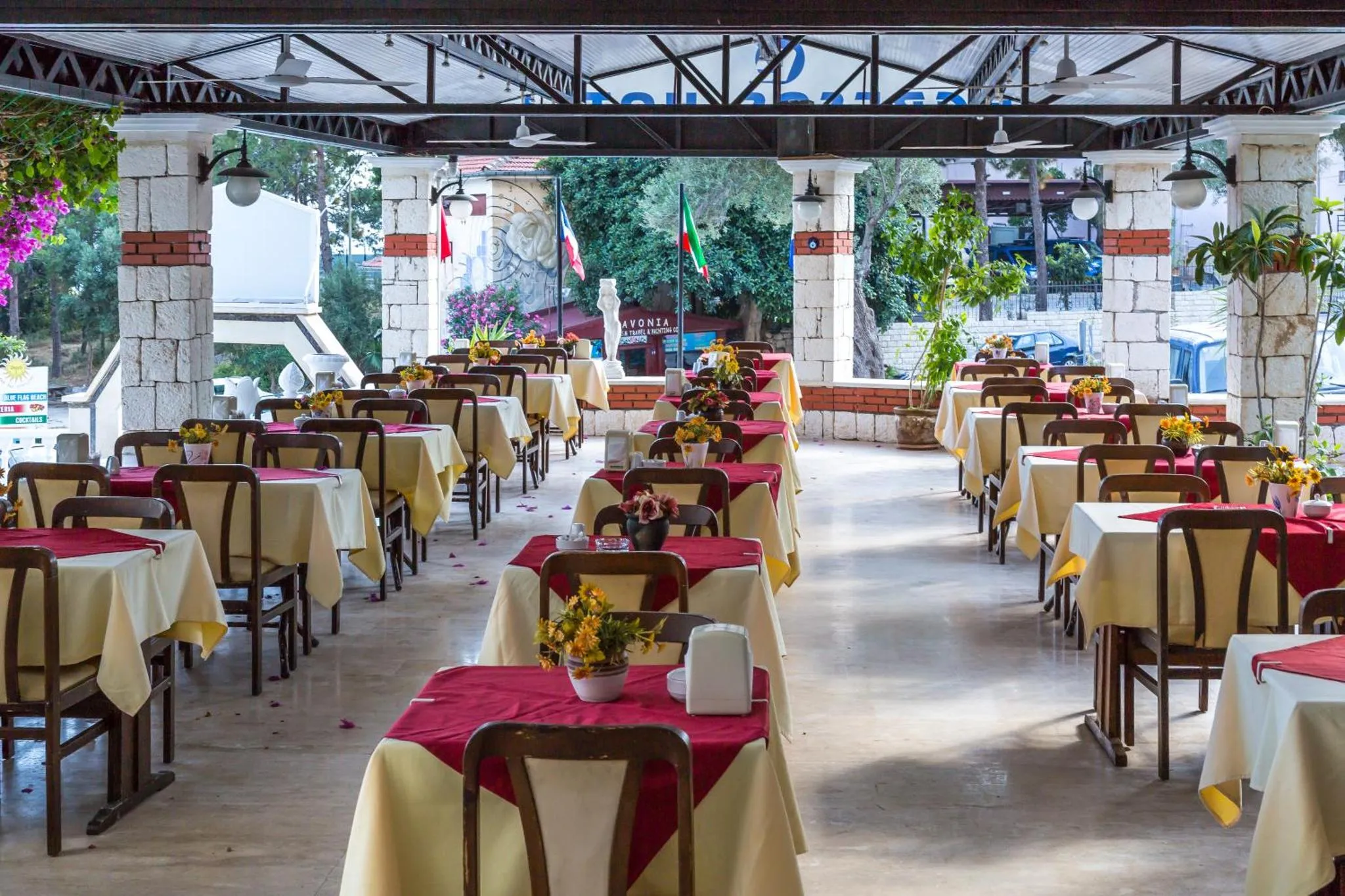 Une salle de restaurant lumineuse avec des tables nappées et des arrangements floraux.