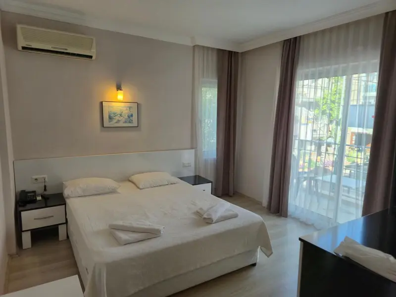 Une chambre lumineuse avec un lit double et un accès à une terrasse.