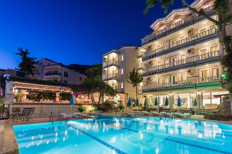 Bâtiment illuminé avec piscine au premier plan et végétation luxuriante.