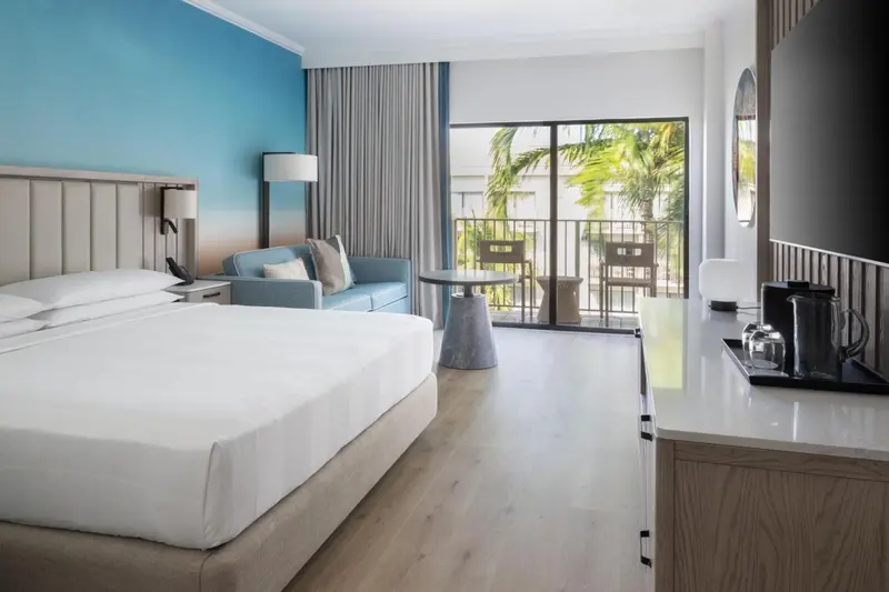 Une chambre lumineuse avec un grand lit et un coin salon donnant sur une terrasse.