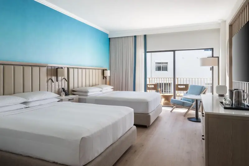 Chambre lumineuse avec deux lits et un espace détente.