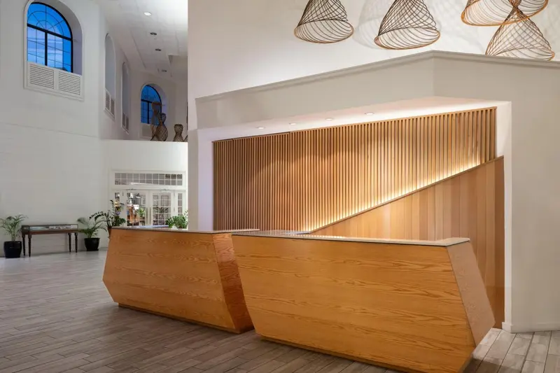 Un comptoir d'accueil en bois clair dans un hall spacieux et lumineux.