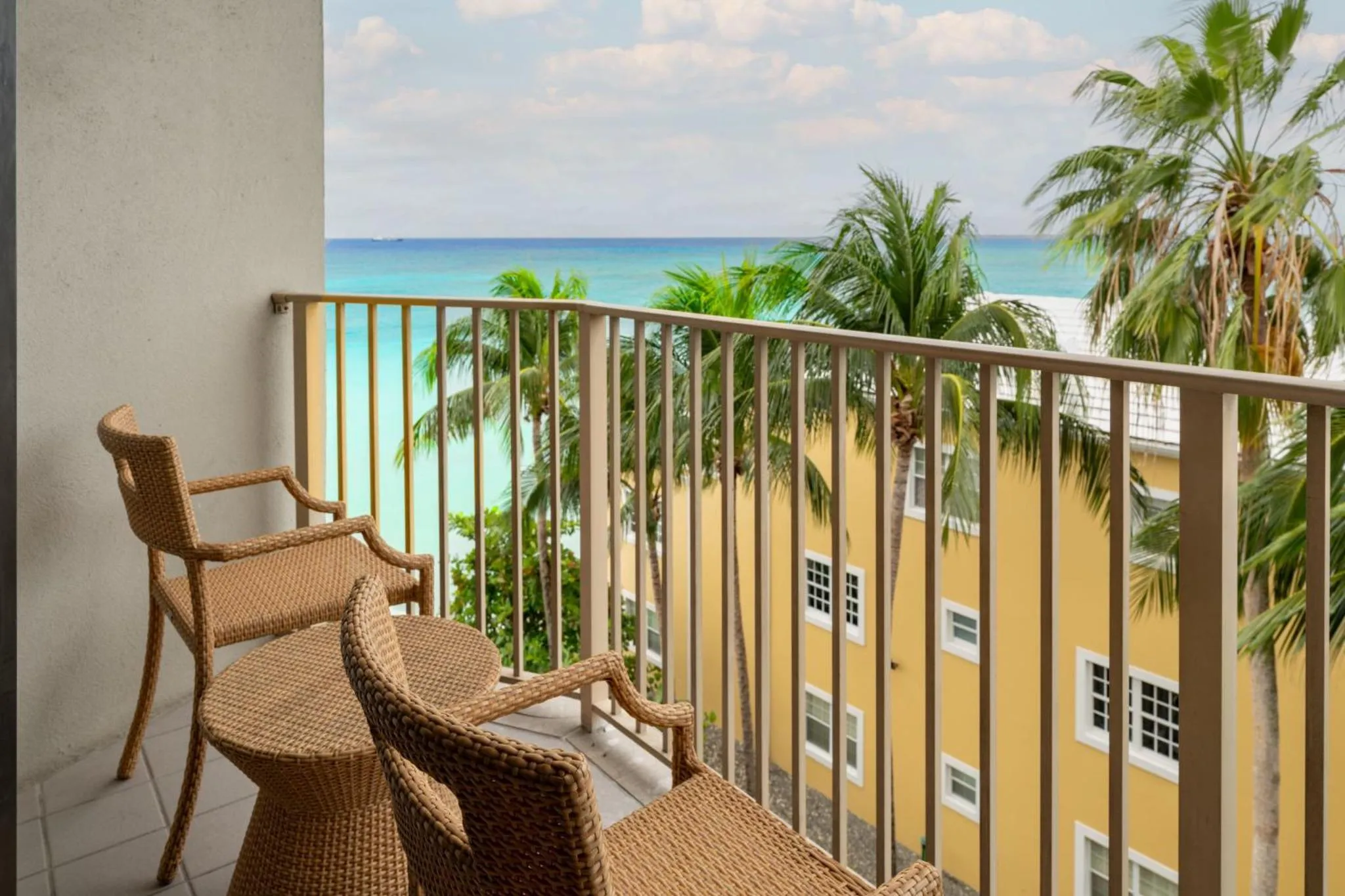 Terrasse avec mobilier en osier donnant sur la mer et la végétation tropicale.
