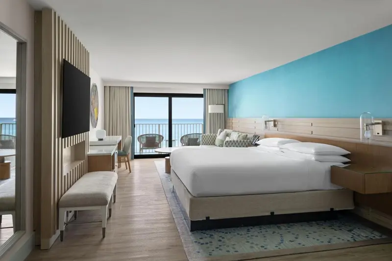 Chambre lumineuse avec un grand lit et vue sur la mer.