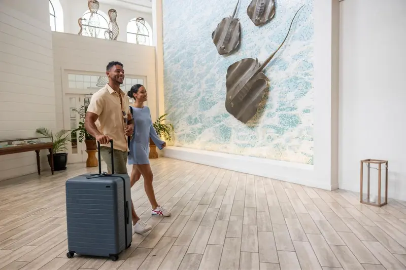 Un couple avec des valises se promène dans un hall d'hôtel décoré de raies.