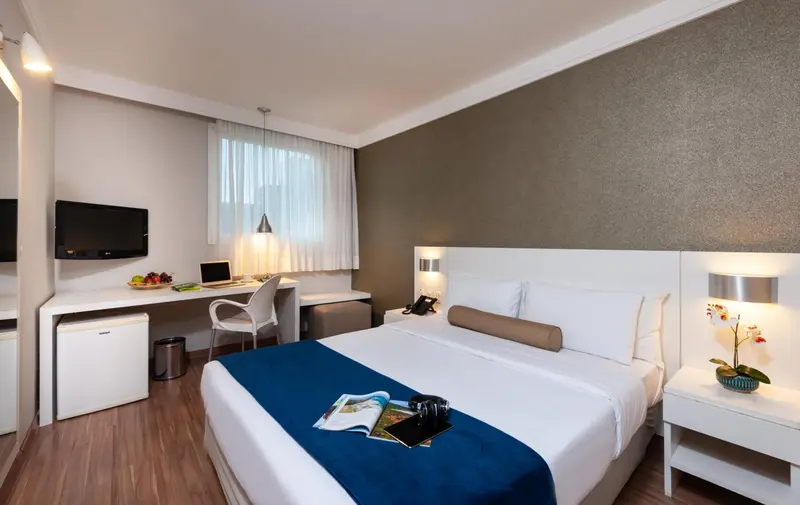 Une chambre lumineuse avec un lit double et un espace bureau.