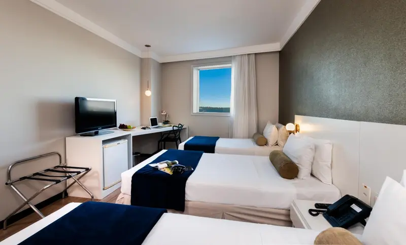 Une chambre d'hôtel lumineuse avec deux lits simples et un bureau.