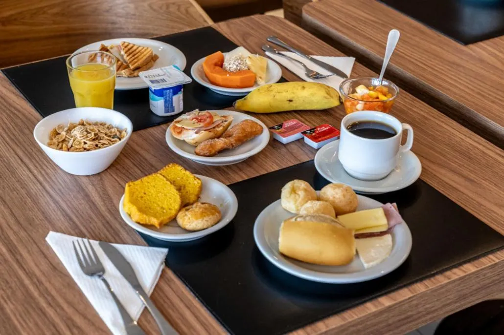 Une table est dressée avec un petit-déjeuner composé de fruits, de viennoiseries et de boissons.