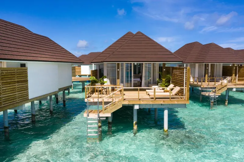Maisons sur pilotis au-dessus d'une eau turquoise et claire.