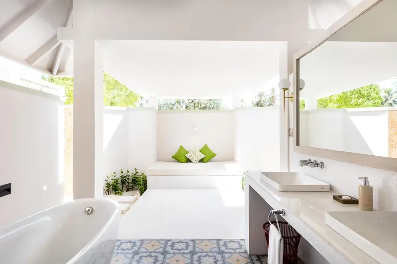 Salle de bain lumineuse avec baignoire et douche à l'extérieur.