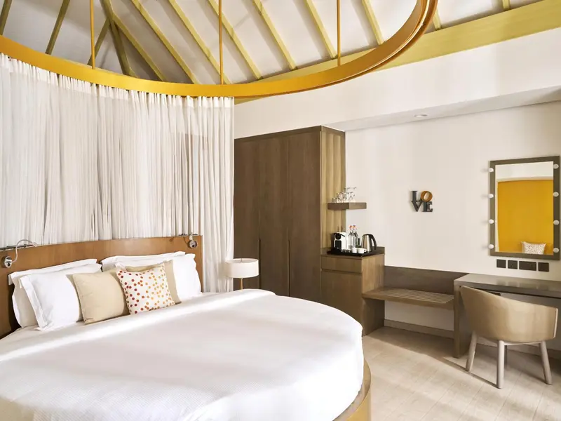 Une chambre lumineuse avec un grand lit et un espace coiffeuse.