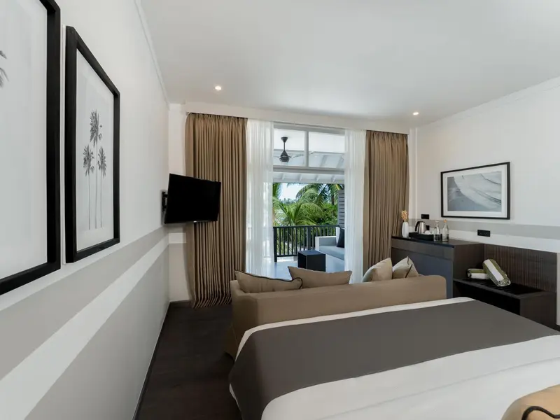 Une chambre lumineuse avec un canapé et un lit face à une baie vitrée.