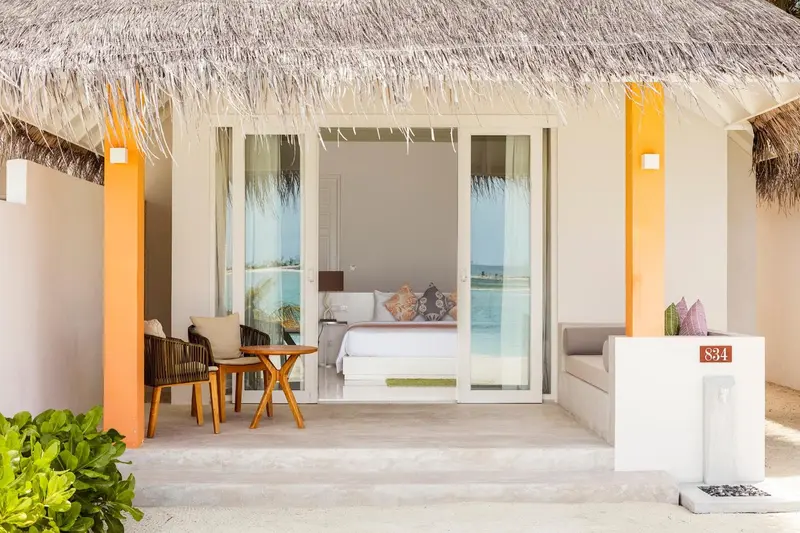 Une chambre lumineuse s'ouvre sur une terrasse avec mobilier en rotin.