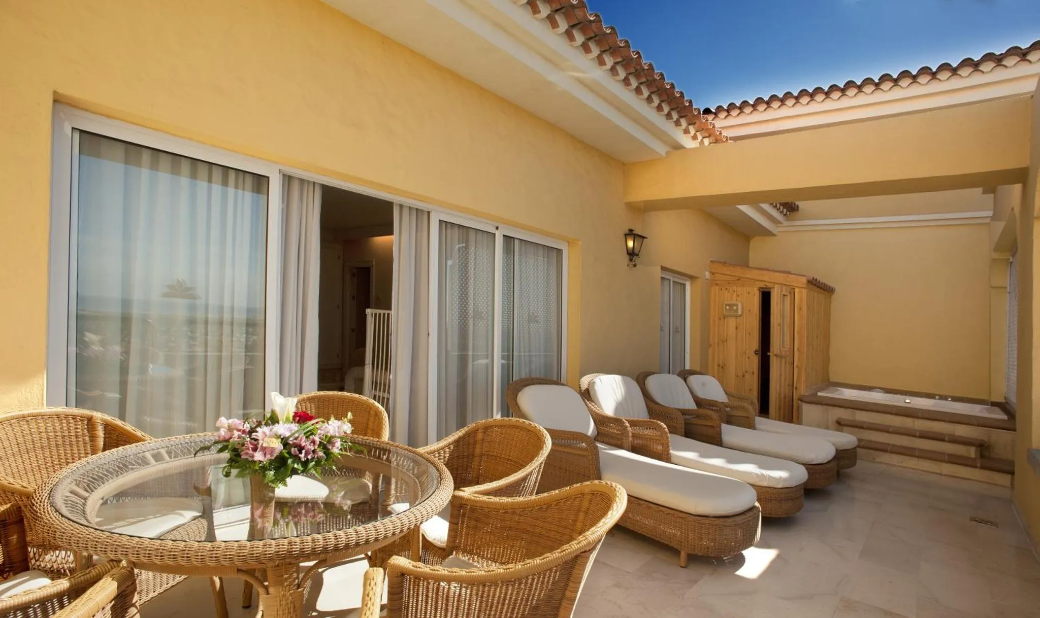 Terrasse aménagée avec mobilier de jardin et vue sur la mer.
