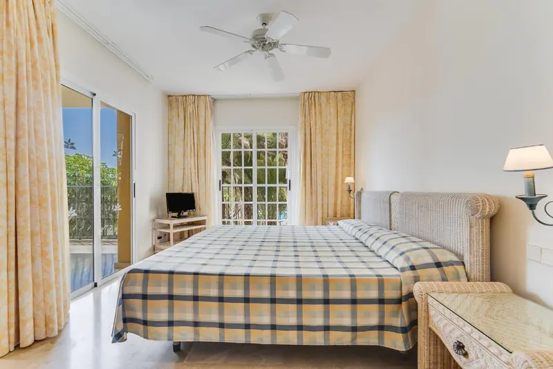 Une chambre lumineuse avec un grand lit et des rideaux clairs.
