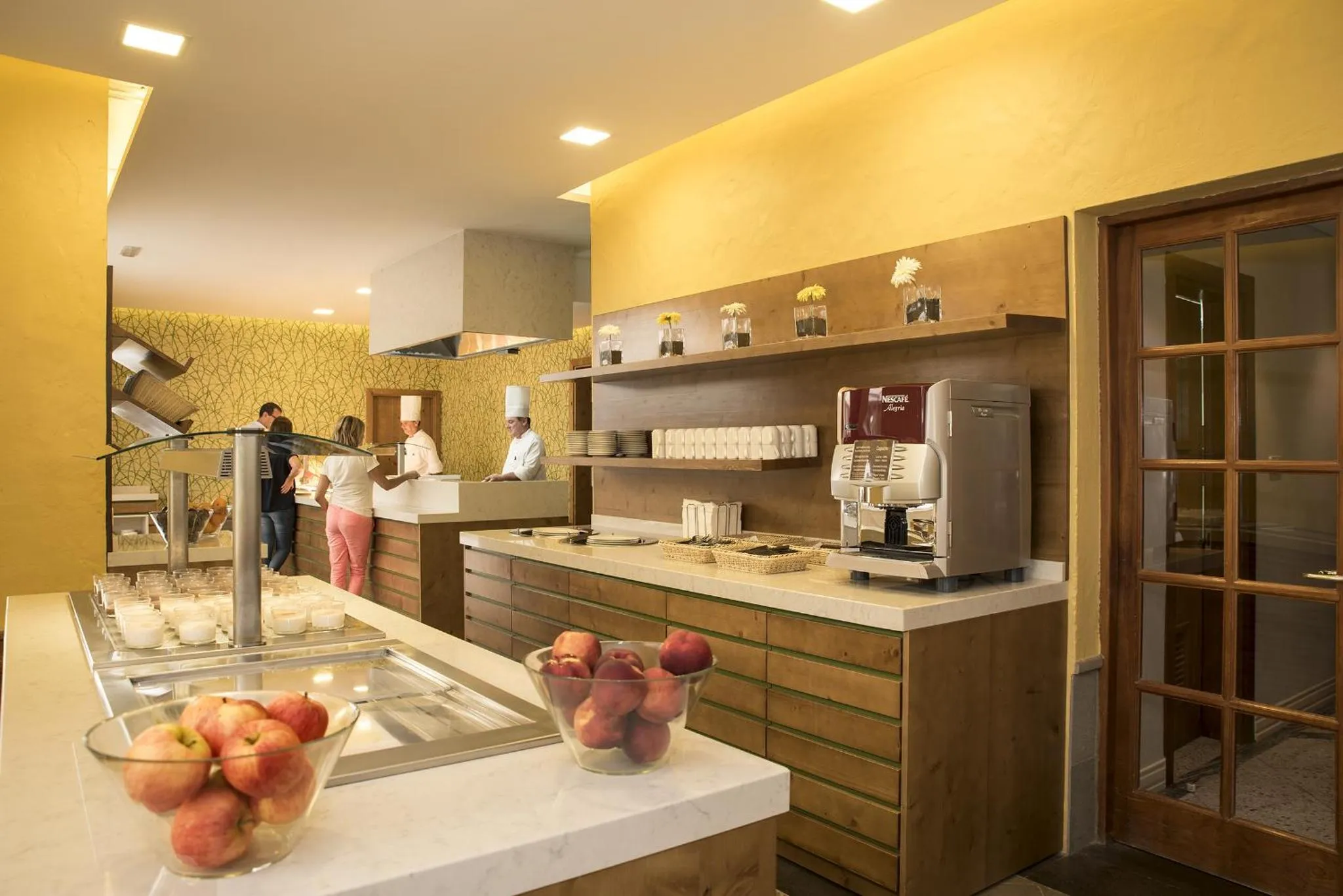 Un buffet propose des fruits frais et des boissons dans une salle lumineuse.