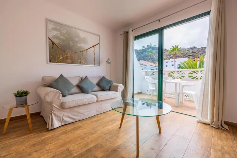 Un salon clair s'ouvre sur une terrasse avec vue sur la végétation.