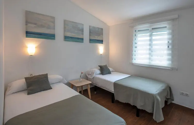 Une chambre lumineuse avec deux lits simples et des tableaux décoratifs.