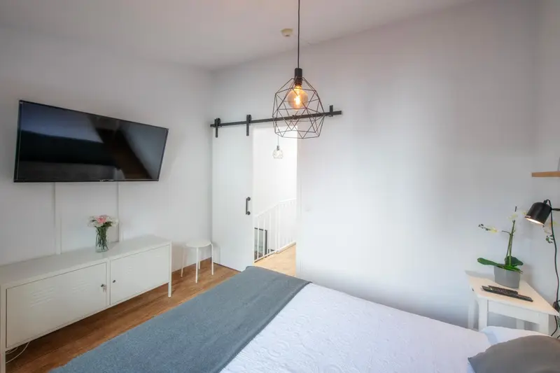 Une chambre lumineuse avec un lit et un téléviseur mural.