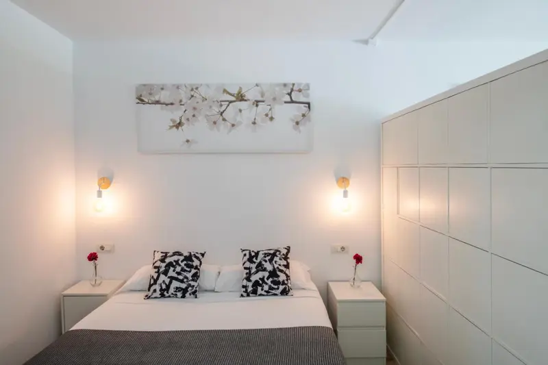Une chambre lumineuse avec un lit double et une décoration florale au mur.