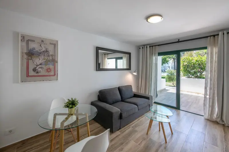Un salon clair avec un canapé gris et une table basse en verre.