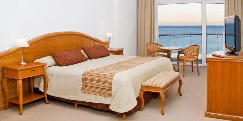 Chambre lumineuse avec un grand lit et une vue sur la mer.