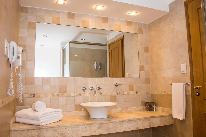Une salle de bain claire avec un grand miroir et des carreaux beiges.
