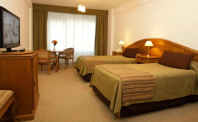 Une chambre lumineuse avec deux lits et un coin salon.