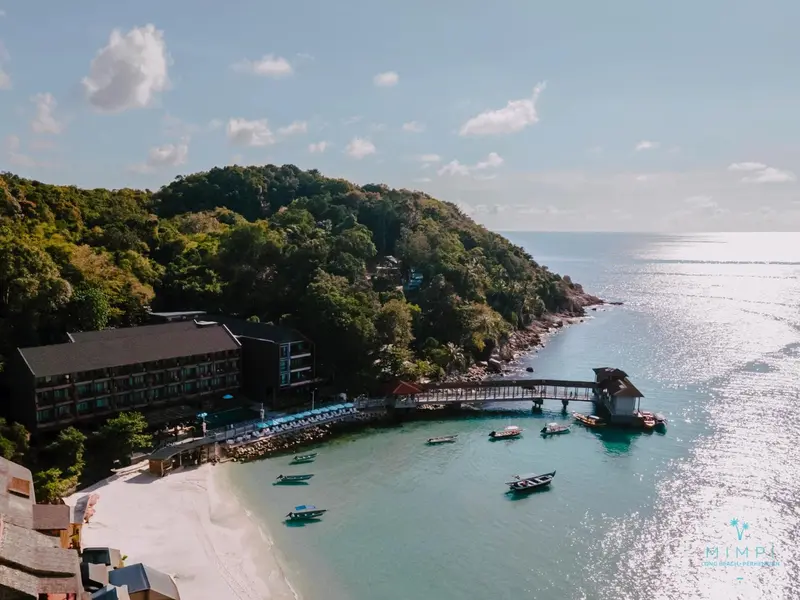 Vue aérienne d'une plage bordée de bâtiments et de petites embarcations.