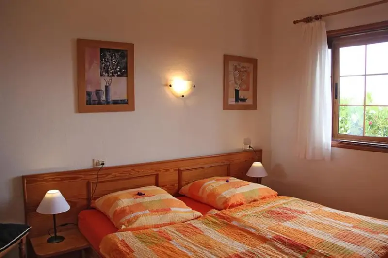 Une chambre lumineuse avec un lit double et des tableaux décoratifs.