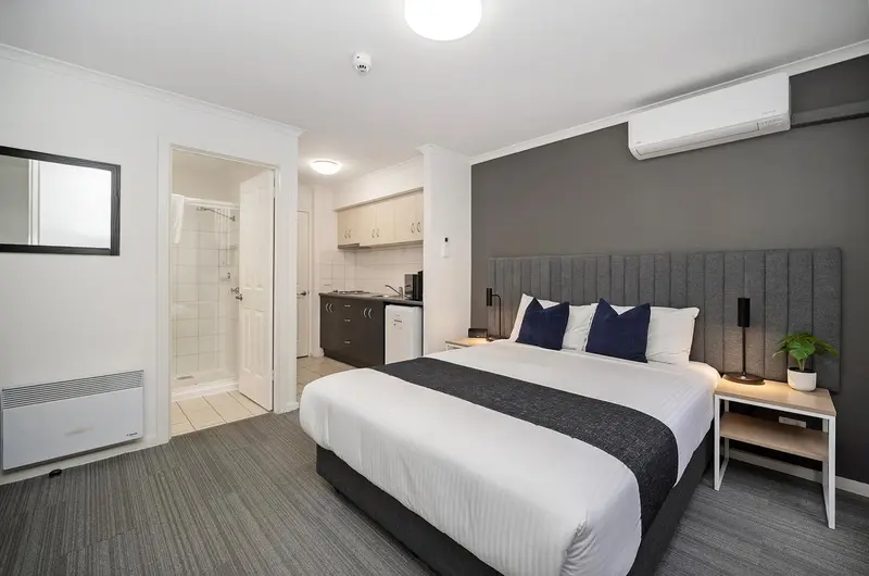 Une chambre avec un lit double et une kitchenette.