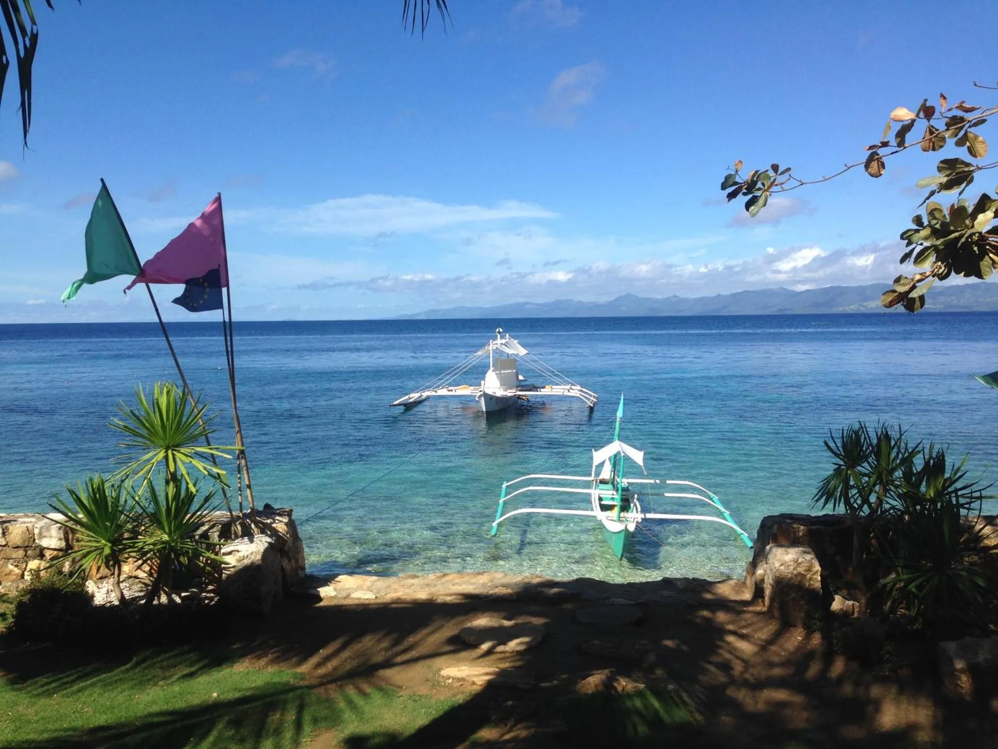 Vue sur la mer depuis une plage avec des embarcations traditionnelles.