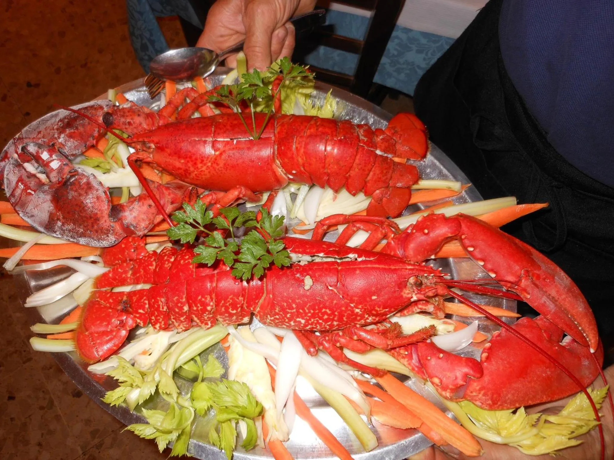 Un plat de homard décoré de légumes frais est présenté sur un grand plateau.