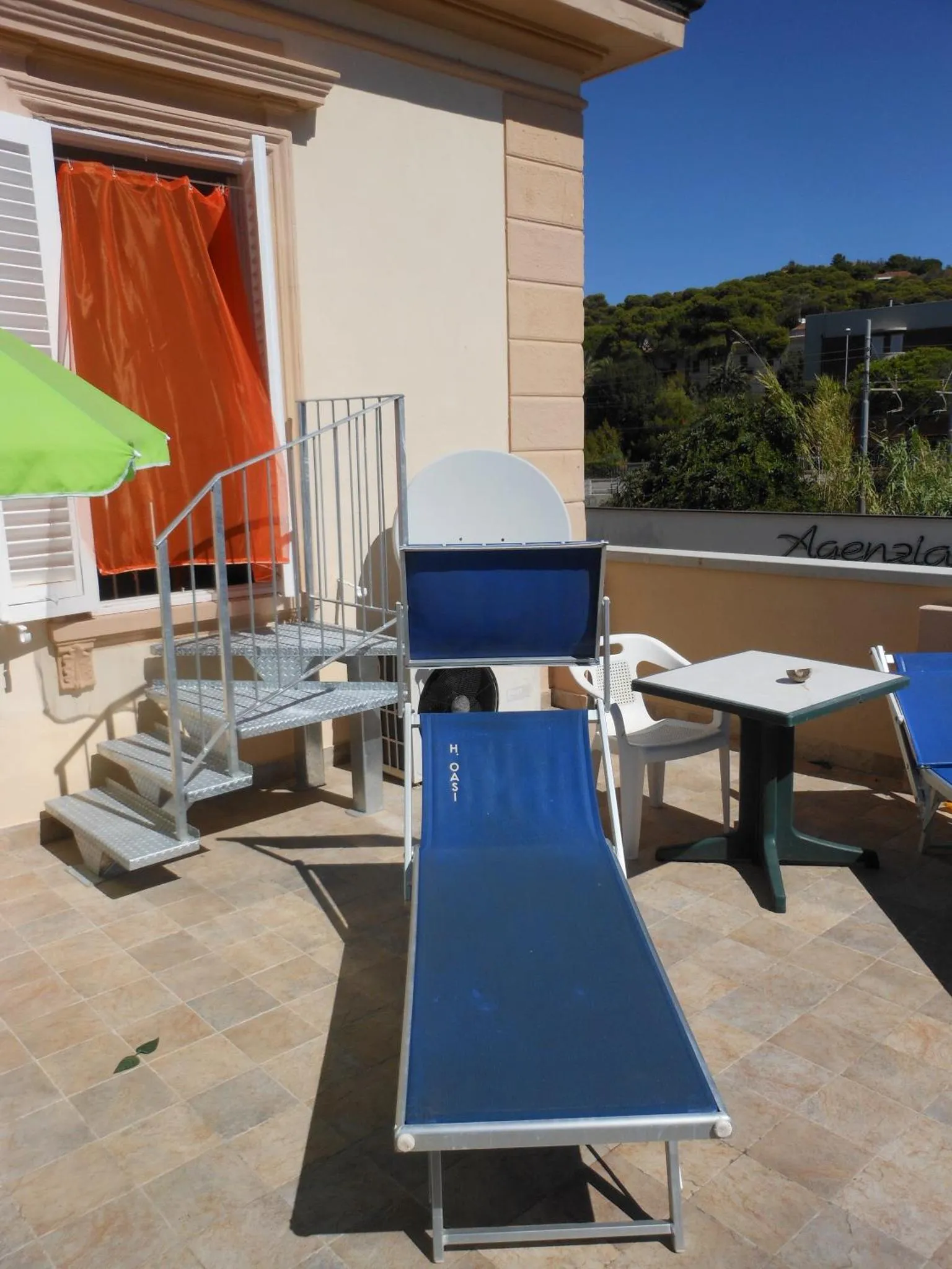 Terrasse avec transats et escalier métallique.