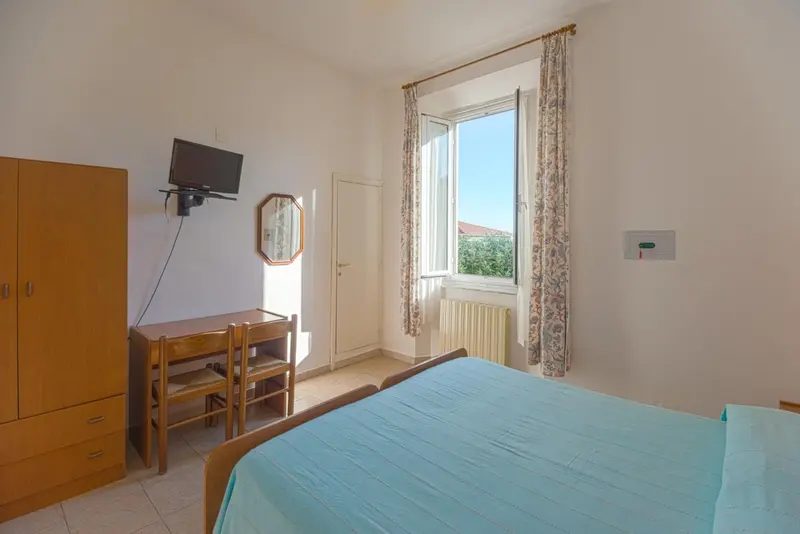 Une chambre lumineuse avec un lit et un bureau près d'une fenêtre.