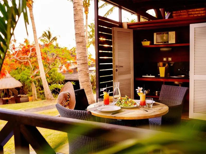 Une table ronde est dressée sur une terrasse avec des chaises et un repas.
