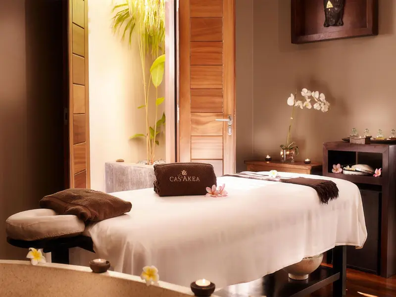 Table de massage recouverte d'un drap blanc dans une pièce lumineuse.