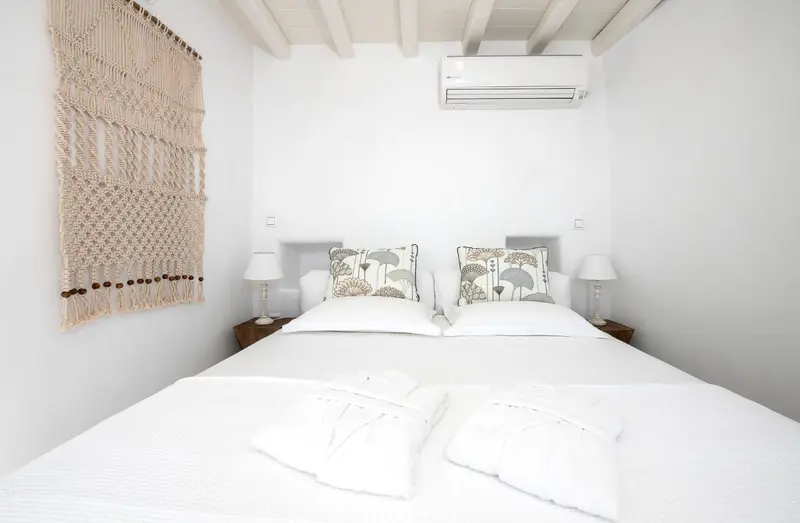 Une chambre lumineuse avec un grand lit et une décoration murale en macramé.