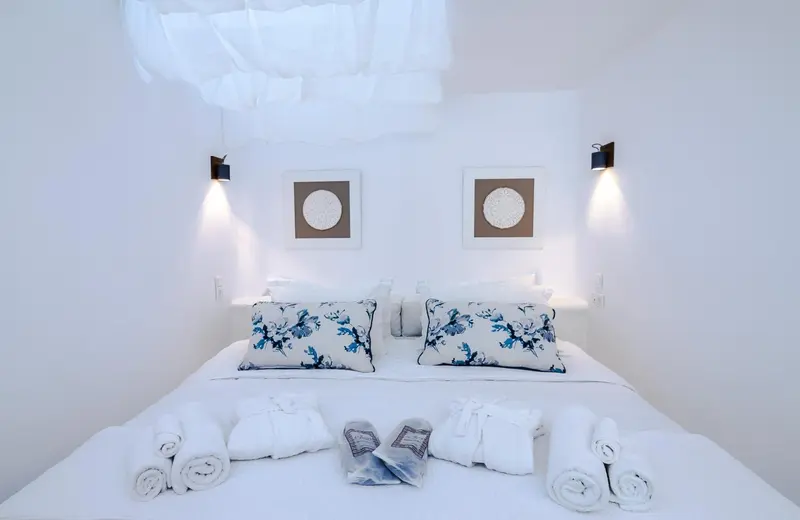 Lit double recouvert d'une moustiquaire et de coussins décorés, dans une chambre lumineuse.