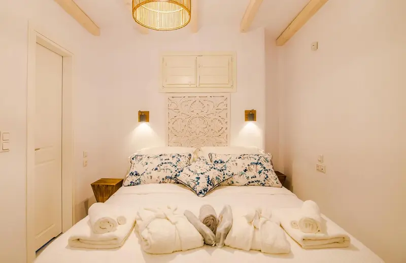Une chambre lumineuse avec un grand lit décoré de coussins et de serviettes pliées en forme d'animaux.