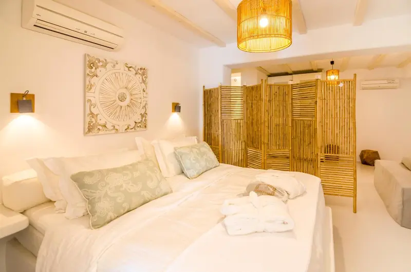 Une chambre lumineuse avec un grand lit recouvert de draps blancs et de coussins.